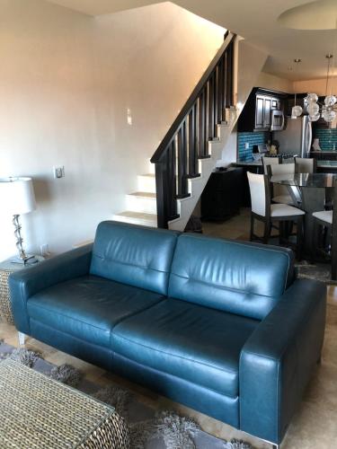 a blue leather couch in a living room with a staircase at The Meridian at Lighthouse Point in West Bay