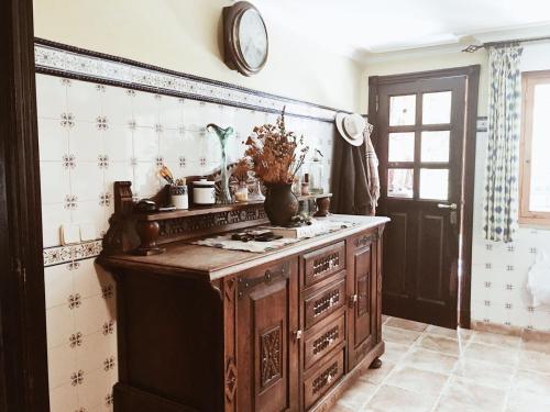 a kitchen with a wooden cabinet and a clock on the wall at Casa Os Curras in Culleredo