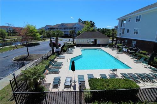 a large swimming pool with chairs and a building at 113 Cypress Bend Condo in North Myrtle Beach