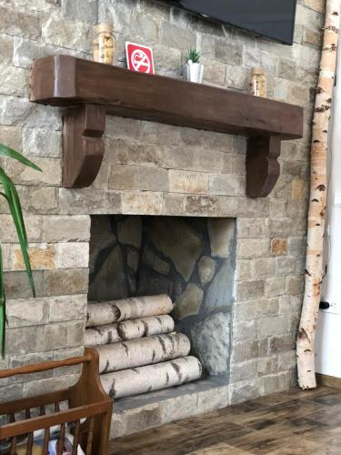 a stone fireplace with a wooden shelf on top at Cabana din Groapa Frumoasa in Râşnov
