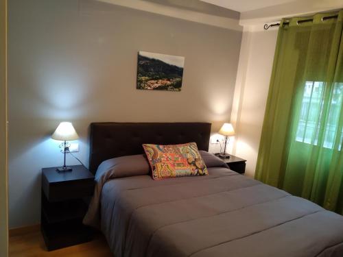 1 dormitorio con 1 cama, 2 lámparas y ventana en Ariosa, en Arroyo Frío