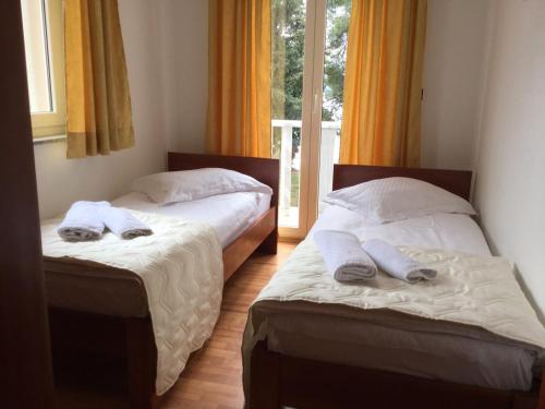 two beds sitting in a room with a window at Apartments Šulekić in Sveti Filip i Jakov
