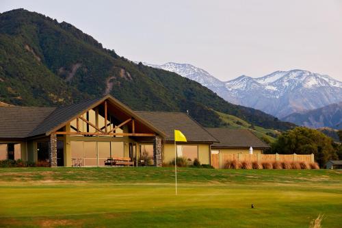 a house on a golf course with mountains in the background at Koura Bay Golf Resort in Kaikoura