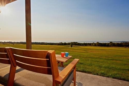 a wooden bench sitting on a patio with a view of a field at Koura Bay Golf Resort in Kaikoura