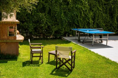 a ping pong table and two chairs in the grass at Thelxis Villa in Lourdhata