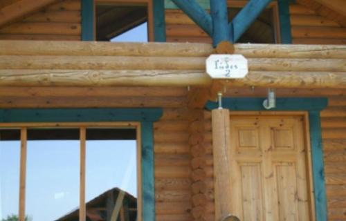 a log cabin with a door and a sign on it at Dionysus Village Resort in Mousthéni