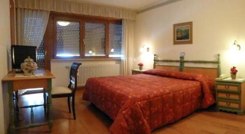 坎皮泰洛迪法薩的住宿－費德拉公園酒店，一间卧室配有红色的床、一张书桌和一张书桌