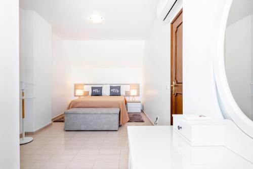 a white bedroom with a bed and a couch at My Place @ Faro Duplex in Faro