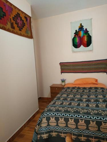a bedroom with a bed and a painting on the wall at Hospedaje Inti in Pisac