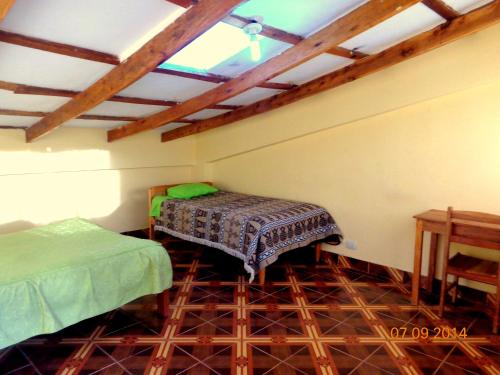 a room with two beds and a table in it at Hospedaje Inti in Pisac