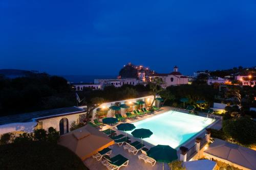 a pool with chairs and umbrellas at night at Hotel Villa Durrueli Resort & Spa in Ischia