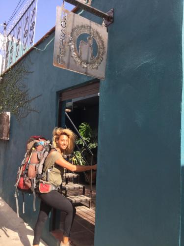 a woman standing outside of a building with a sign at Trotamundo Oaxaca Hostel in Oaxaca City