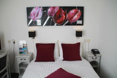 a bedroom with a white bed with red pillows at De Doelen in Leiden
