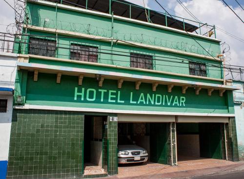 a green hotel building with a car parked in front at Hotel Landivar Zona 7 in Guatemala