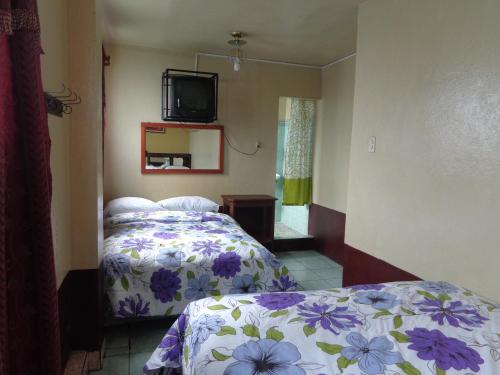 - une chambre avec un lit et une télévision murale dans l'établissement Hotel Landivar Zona 7, à Guatemala