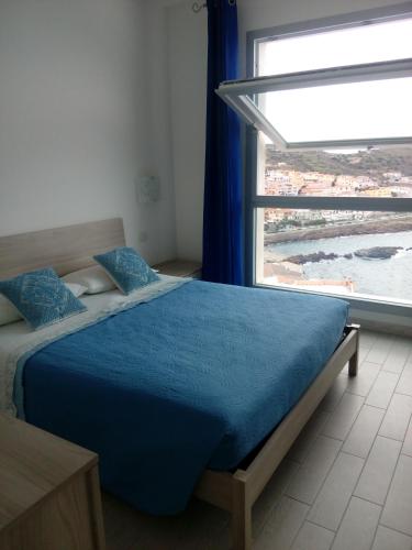 a bedroom with a blue bed with a large window at La bella vista in Castelsardo