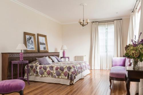 a bedroom with a bed and two purple chairs at Casa Chacabuco Tandil in Tandil
