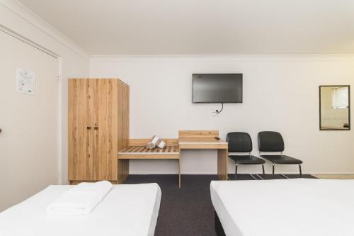 Habitación con 2 camas y escritorio con 2 sillas. en Metro Motel Rockhampton en Rockhampton