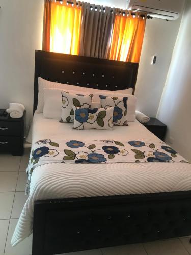 um quarto com uma cama com uma cabeceira e almofadas pretas em Ave. Duarte k3/12, Residencial Palma Real, Santiago, RD em Arenoso