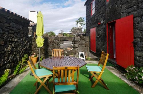 uma mesa de madeira com cadeiras e um guarda-sol num quintal em Casas Alto da Bonança em São Roque do Pico