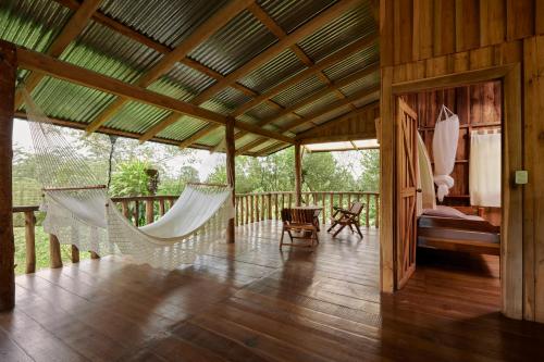 um alpendre com redes de descanso, um quarto e uma cama em Finca Amistad Cacao Lodge em Bijagua