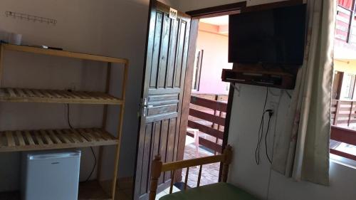 Zimmer mit einem TV und einem Zimmer mit einem Balkon. in der Unterkunft Pousada vila oeste in Itapoa