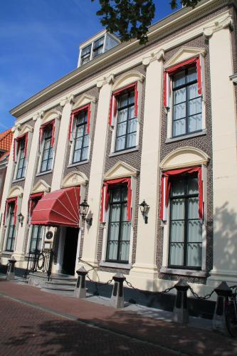 a building with red shuttered windows on a street at De Doelen in Leiden