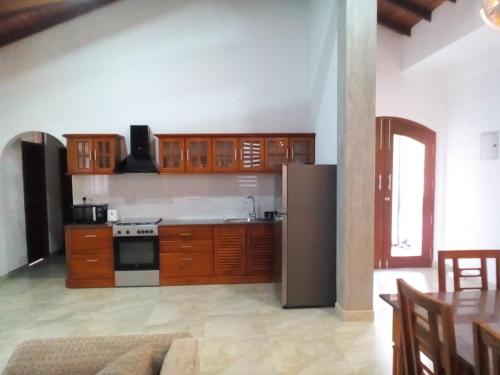 a kitchen with wooden cabinets and a stainless steel refrigerator at Orchid Dream in Bentota