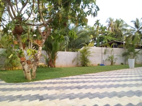 a fence in front of a yard with a tree at Orchid Dream in Bentota