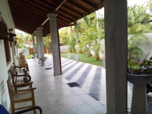 a porch of a house with chairs and palm trees at Orchid Dream in Bentota