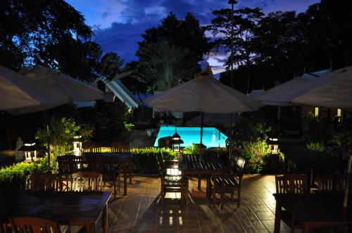an outdoor restaurant with tables and umbrellas at night at Le Passe-Temps in Tha Lane Bay