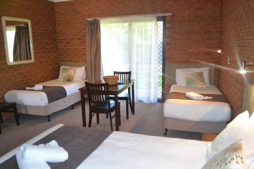 a room with two beds and a table and a window at Ashleigh Court Motor Inn in Mulwala