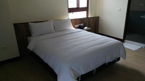 ein großes weißes Bett in einem Schlafzimmer mit Fenster in der Unterkunft Tropical Fish B&B in Magong