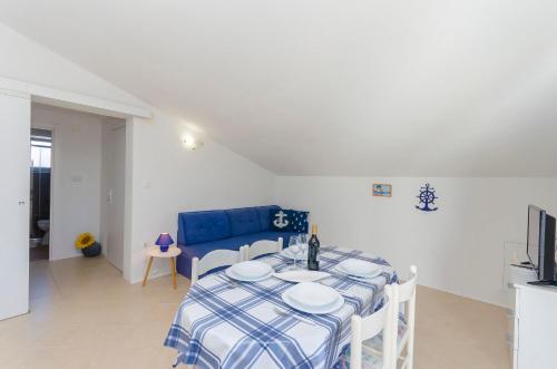 a dining room with a table and a blue couch at Apartments Snjezana in Pirovac