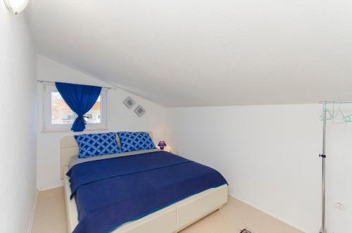 a bedroom with a bed with blue sheets and a window at Apartments Snjezana in Pirovac