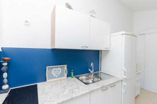 a kitchen with a sink and a blue wall at Apartments Snjezana in Pirovac