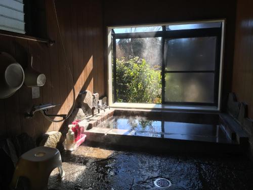 La salle de bains est pourvue d'un lavabo et d'une fenêtre avec de l'eau. dans l'établissement 山荘 紗羅樹 Syaranoki, à Yufu