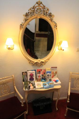a table with a mirror on a wall and a table with books at De Doelen in Leiden