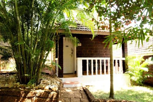 a brick house with a white door and some trees at Namaste Yoga Farm in Gokarna