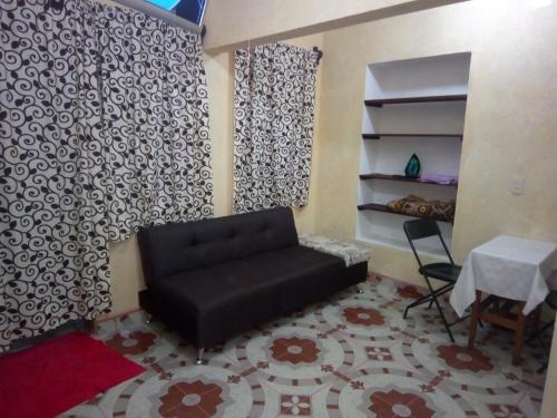 a living room with a black couch and a table at Hospedaje Casa Cortés - Recamaras de Descanso, Tepoztlán Mor - NO CONTAMOS CON ESTACIONAMIENTO in Tepoztlán