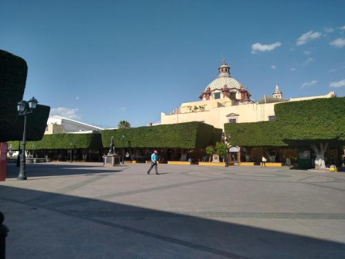 a man walking in a courtyard in front of a building at Hotel Cuauhtemoc in Querétaro