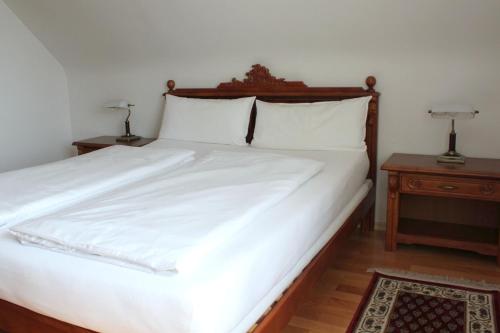 a bedroom with a large white bed with two night stands at Hotel Viktoria in Meersburg