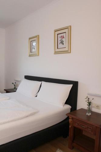 a bed with white sheets and two pictures on the wall at Hotel Viktoria in Meersburg
