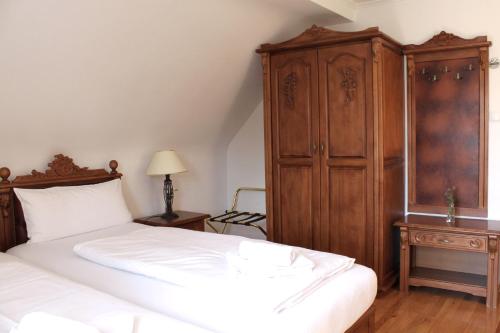 a bedroom with a bed and a wooden cabinet at Hotel Viktoria in Meersburg