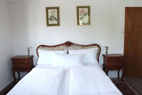 a bedroom with a white bed with two night stands at Hotel Viktoria in Meersburg