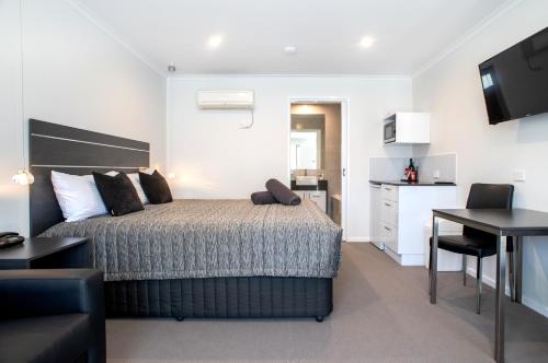 a bedroom with a bed and a table and a desk at Tea House Motor Inn in Bendigo