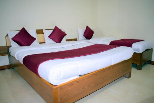 two beds in a room with purple and white pillows at Manas Homestay by Sky Stays in Saputara