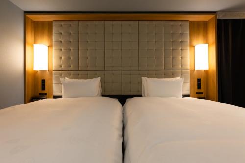 two beds in a hotel room with white sheets at The Royal Park Canvas - Ginza 8 in Tokyo