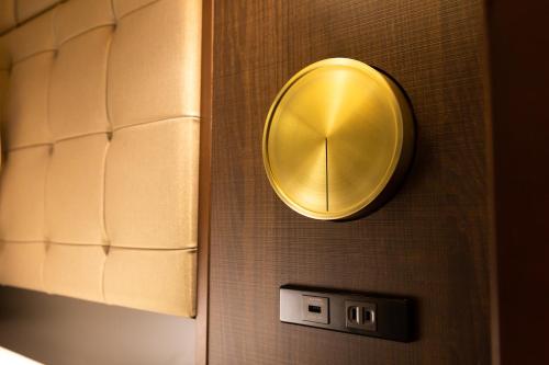 a gold mirror on a wall with a clock at The Royal Park Canvas - Ginza 8 in Tokyo