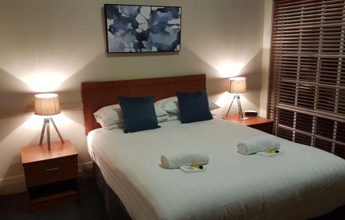 a bedroom with a large bed with two lamps at Highlands Hotel in Mittagong